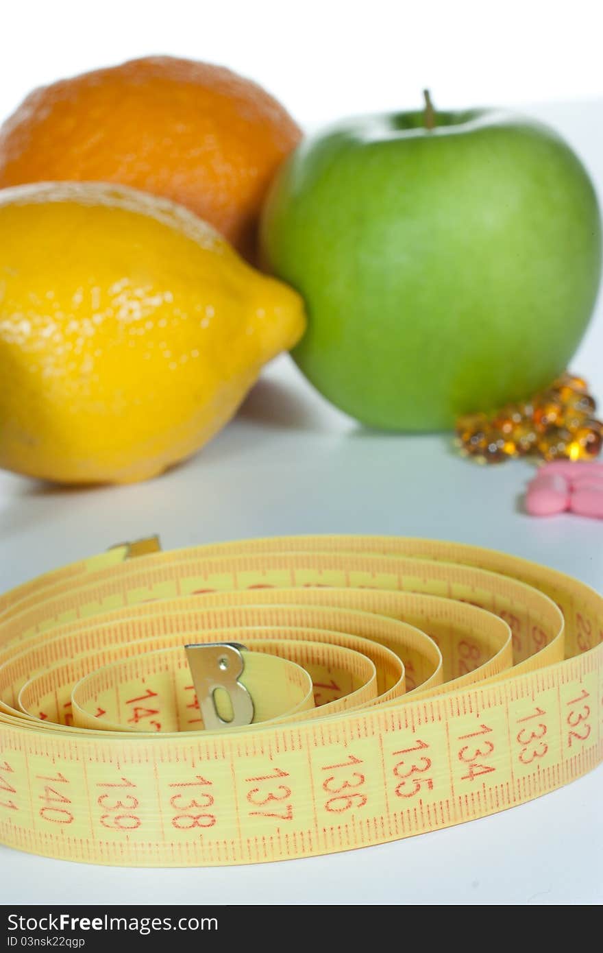 Tape measure, diet pills and fruits isolated on a white background