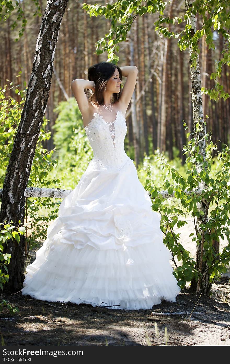 Bride lacing white shoes in the forest