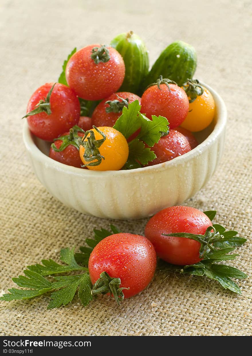 Cherry tomatoes and cucumber in a bowl with parsley. Selective focus. Cherry tomatoes and cucumber in a bowl with parsley. Selective focus