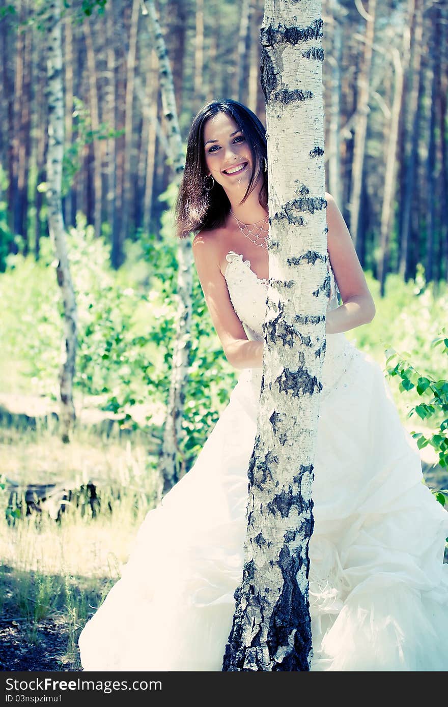 Bride with dark-brown hair posing in forest