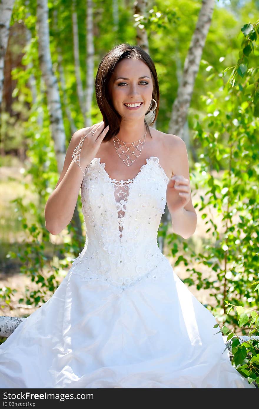 Bride with dark-brown hair posing in forest