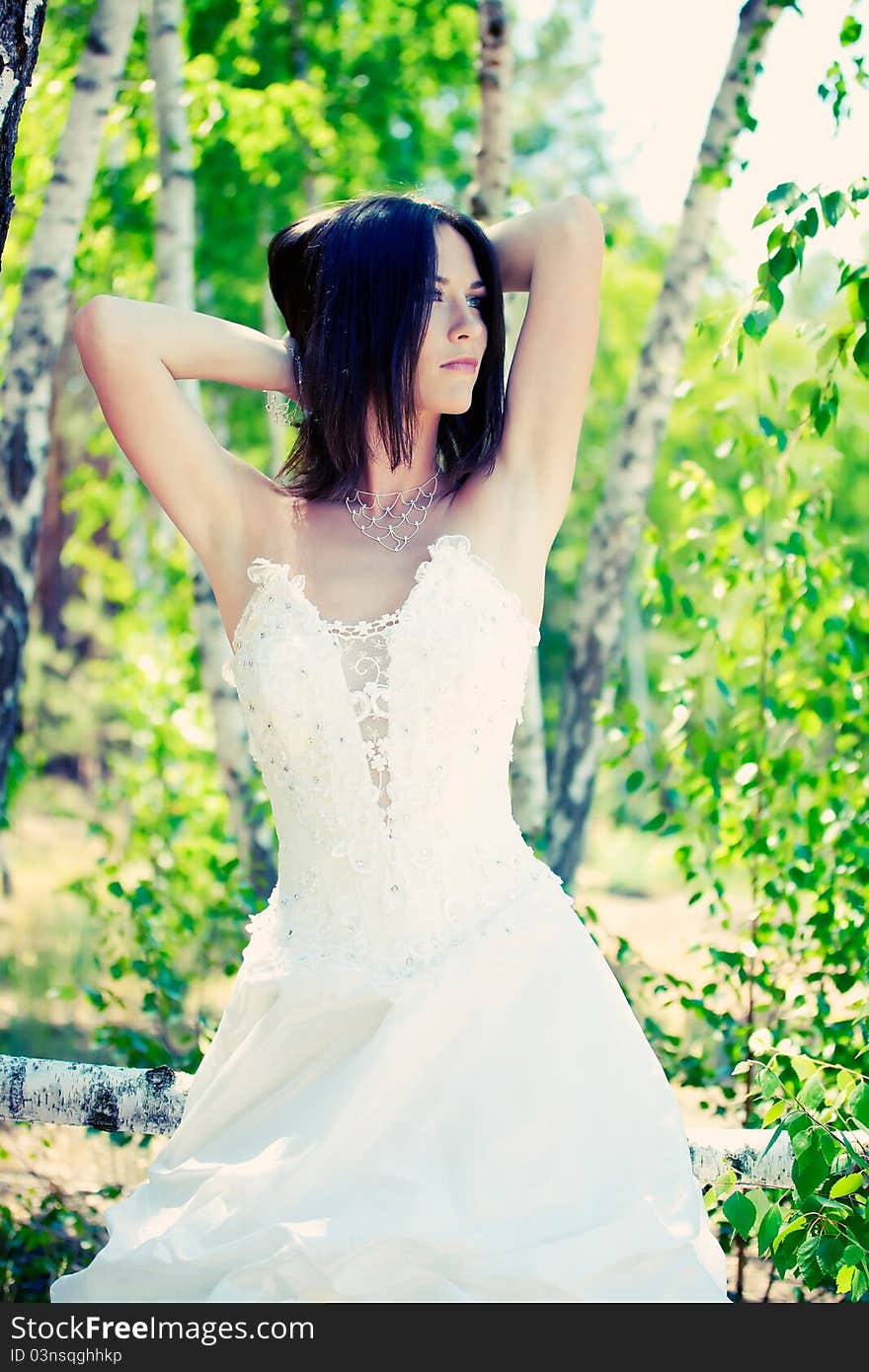 Bride with dark-brown hair posing in forest