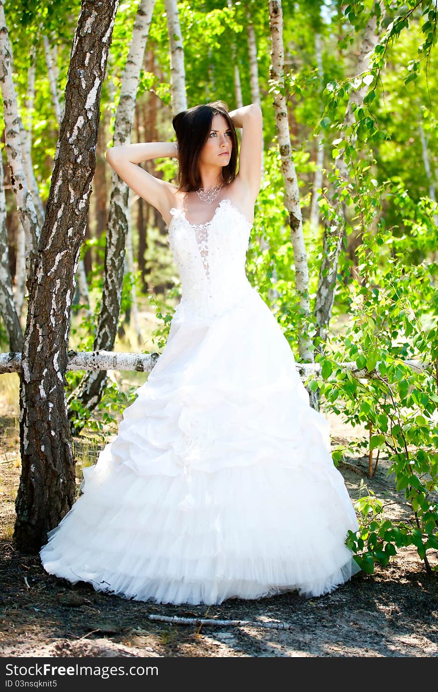 Bride with dark-brown hair posing in forest