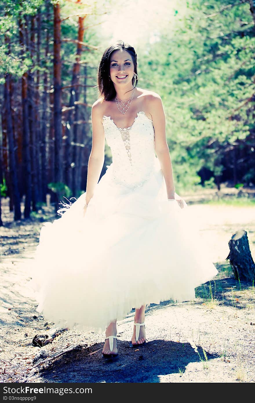 Bride with dark-brown hair posing in forest