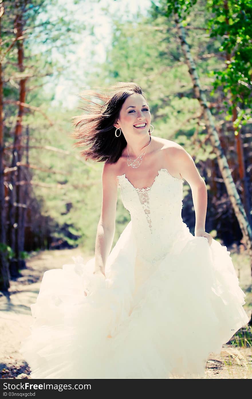 Bride with dark-brown hair posing in forest