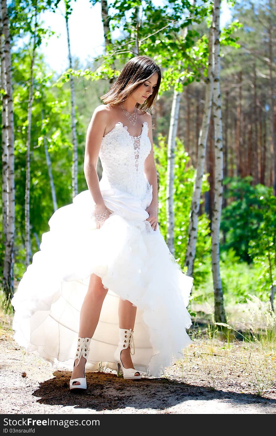 Bride with dark-brown hair posing in forest