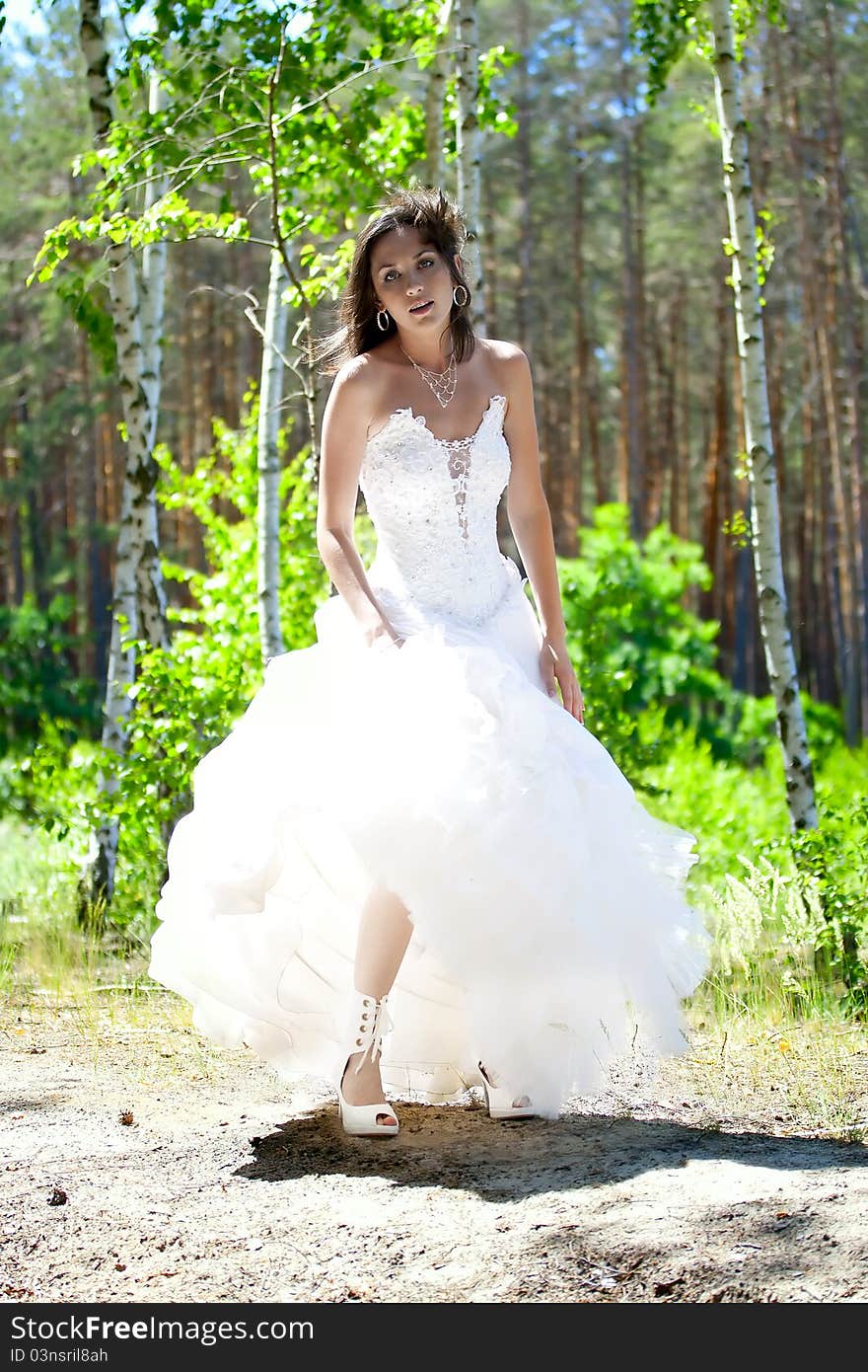 Bride with dark-brown hair posing in forest