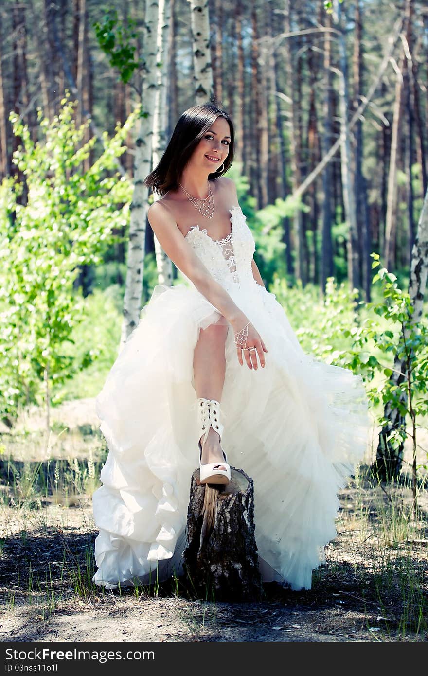 Bride with dark-brown hair posing in forest