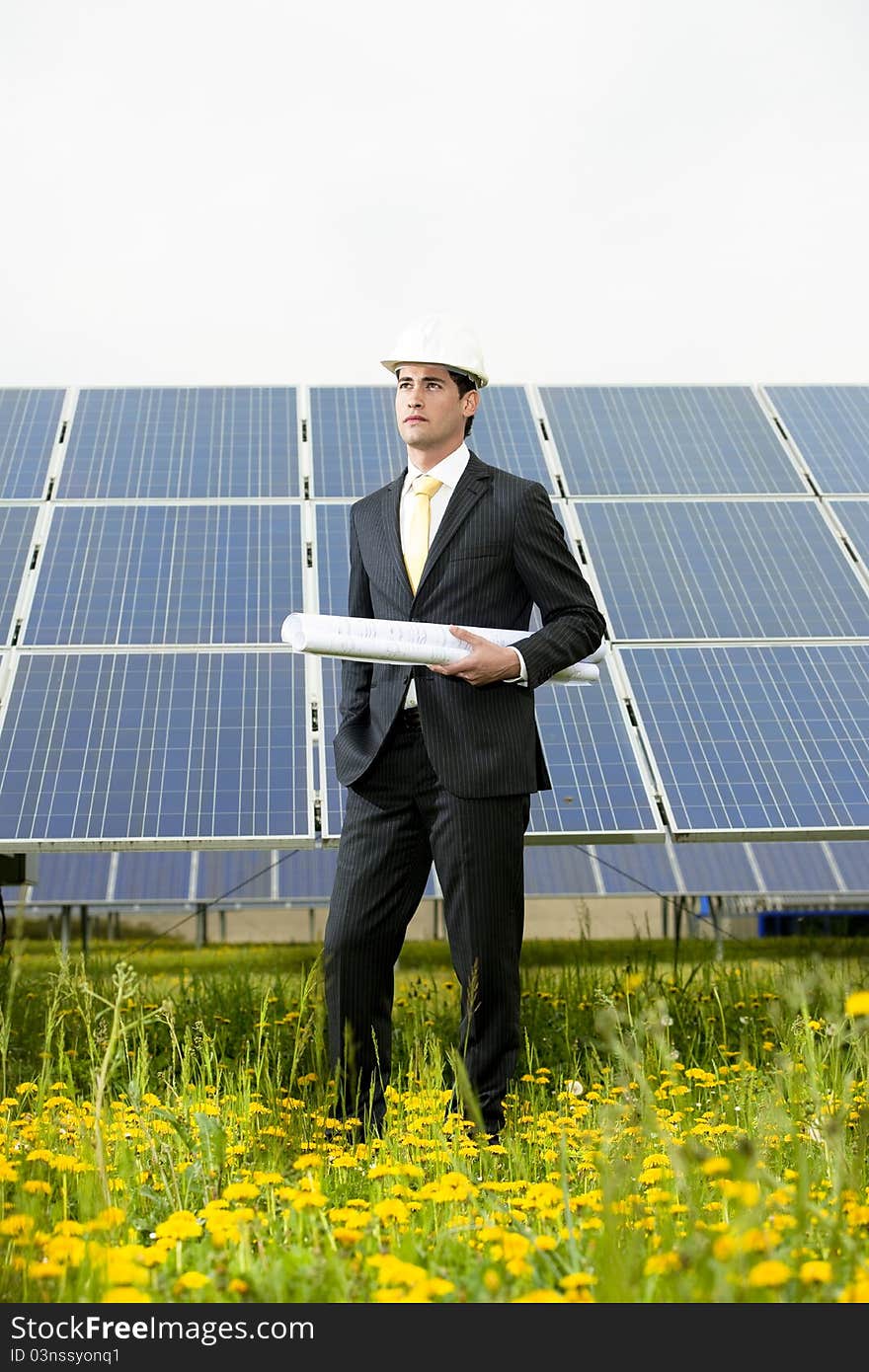 Male engineer at solar power station holding blueprints.