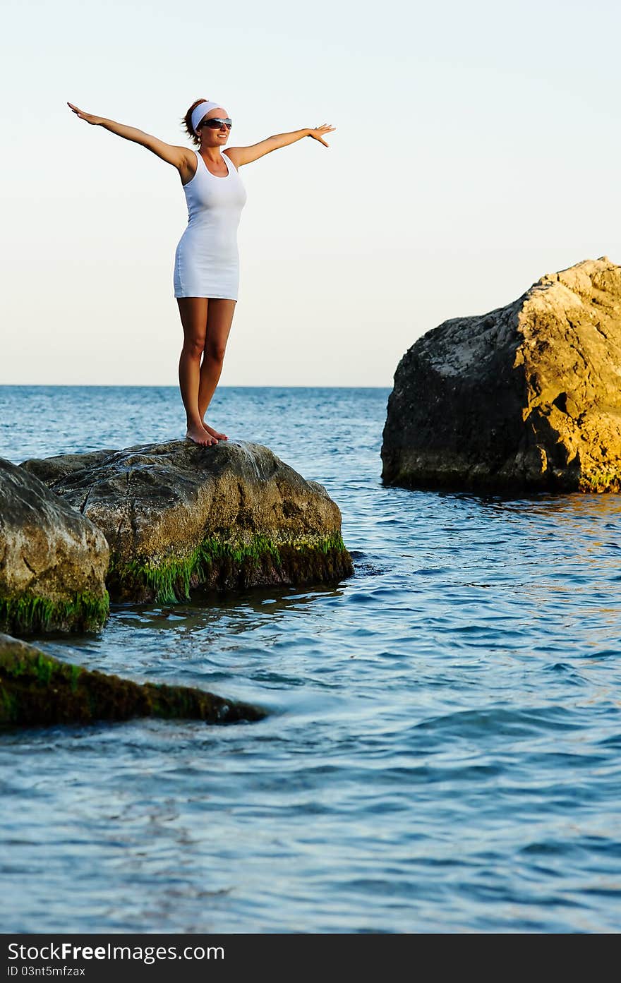 Smiling girl with arms raised towards the sky on sunny day on sunrise