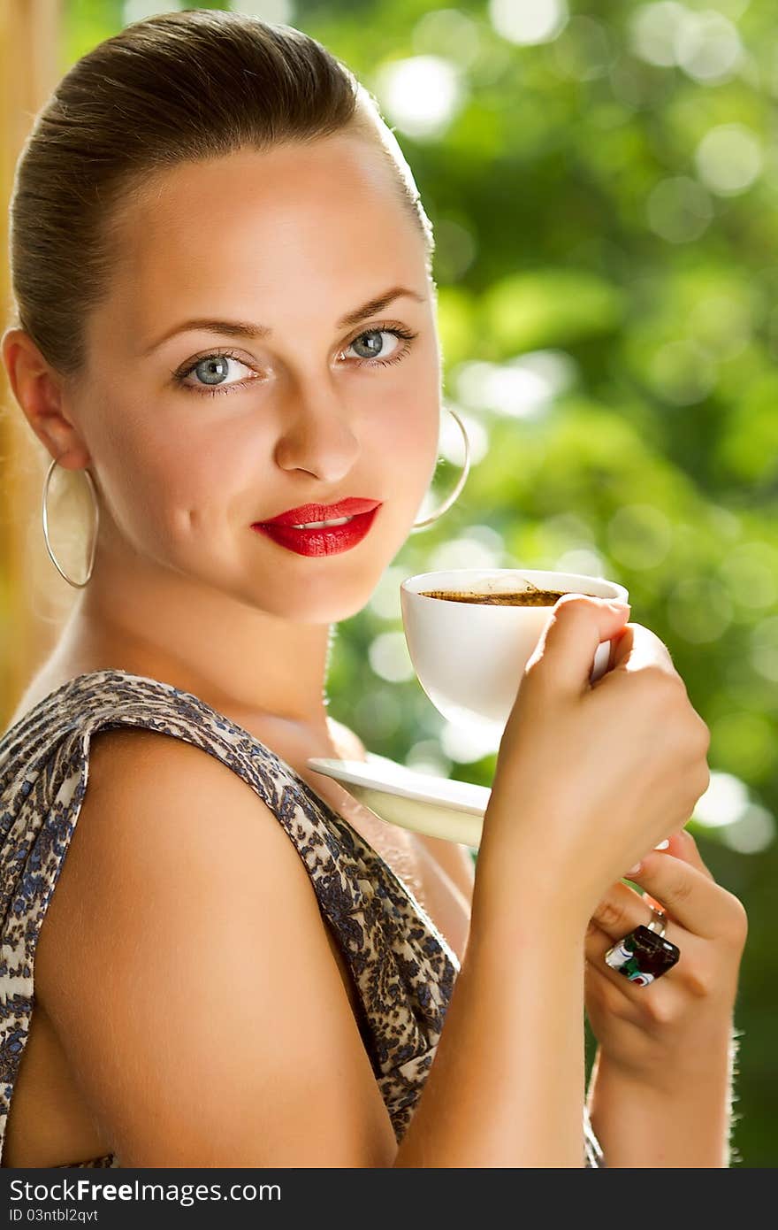 A young attractive woman with a cup of coffe near the window