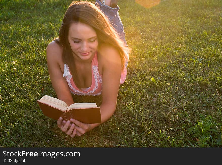 Woman reading and laying down and propped up on her elbows.