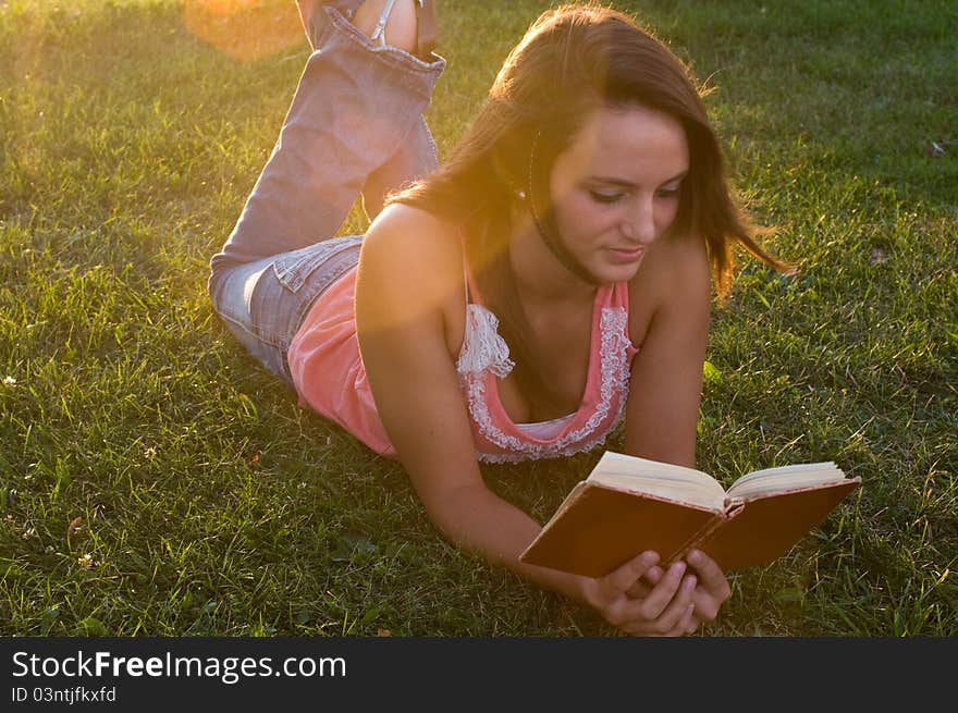 Woman laying down and reading in the twilight of the day. Woman laying down and reading in the twilight of the day.