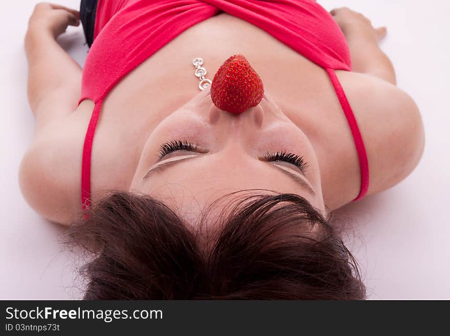 The pretty young woman has a strawberry on the nose. The pretty young woman has a strawberry on the nose