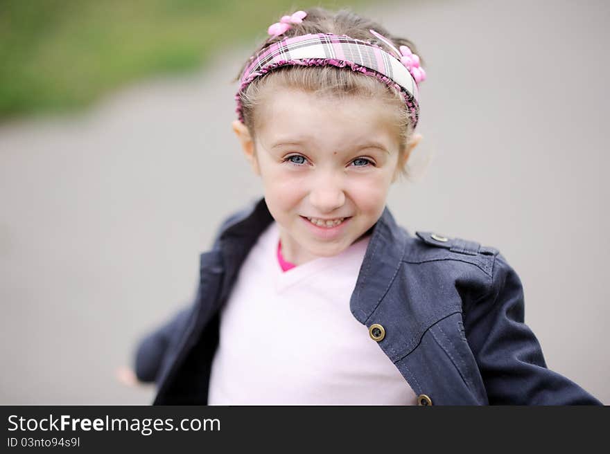 Cute child girl wearing pink headband makes happy smiling face. Cute child girl wearing pink headband makes happy smiling face