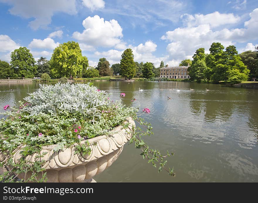 Small lake on an estate in a beautiful rural setting with large flower pot in the foreground. Small lake on an estate in a beautiful rural setting with large flower pot in the foreground