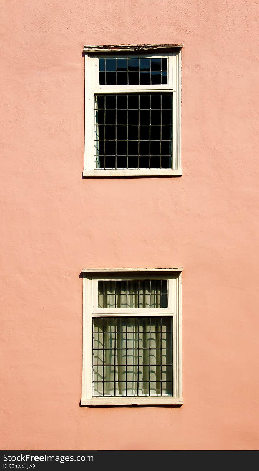 Two old style windows on a pink wall