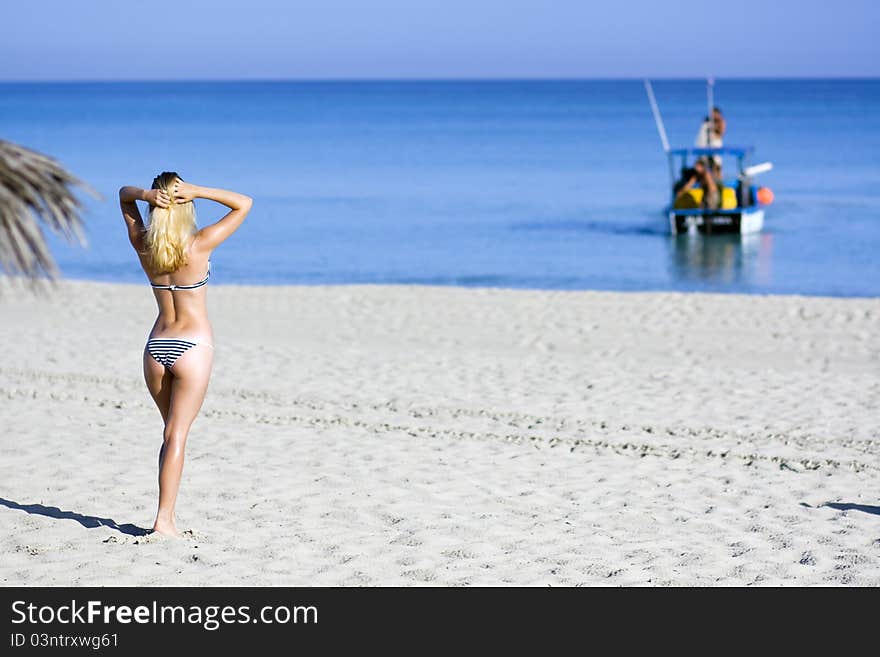 Pretty woman in stripped bikini is looking at the sea. Pretty woman in stripped bikini is looking at the sea