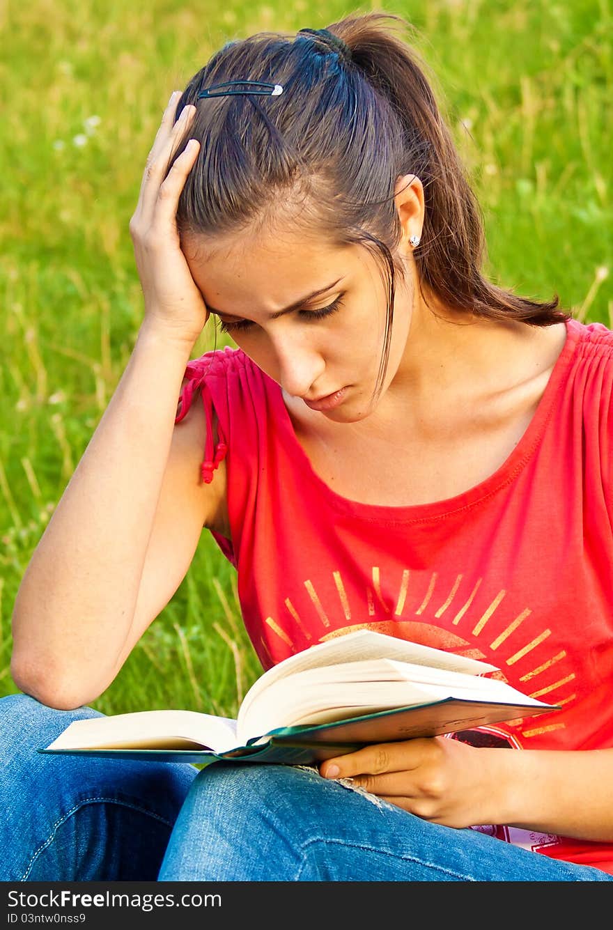 Portrait of a young beautiful woman reading a book in the park. Portrait of a young beautiful woman reading a book in the park