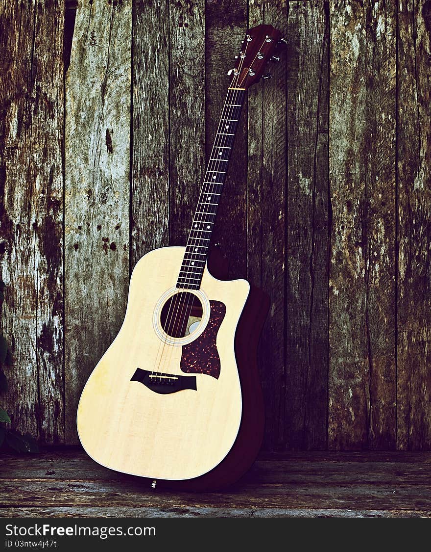 Richly toned image of a classical guitar on a grunge wood backdrop with copy space. Richly toned image of a classical guitar on a grunge wood backdrop with copy space.