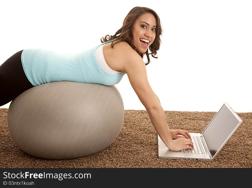 A woman laying on her exercise ball working on the computer. A woman laying on her exercise ball working on the computer.