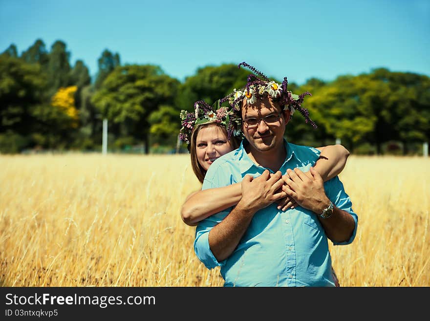 Couple with flowers crowns huging in a field