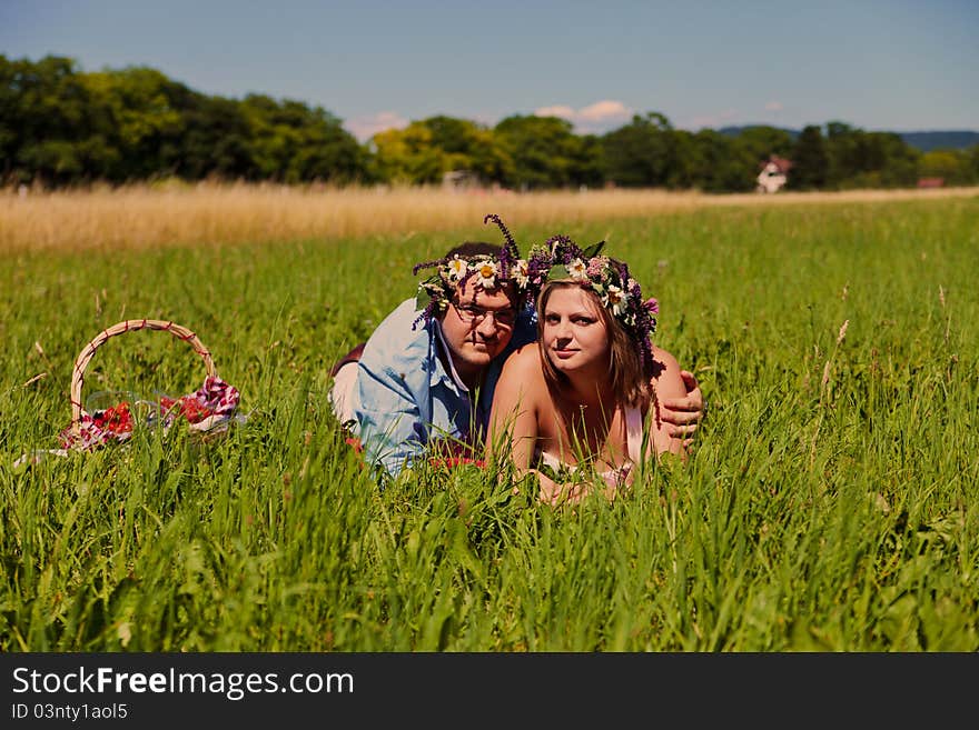 Happy middle aged couple with flowers crown resting on a grass. Happy middle aged couple with flowers crown resting on a grass