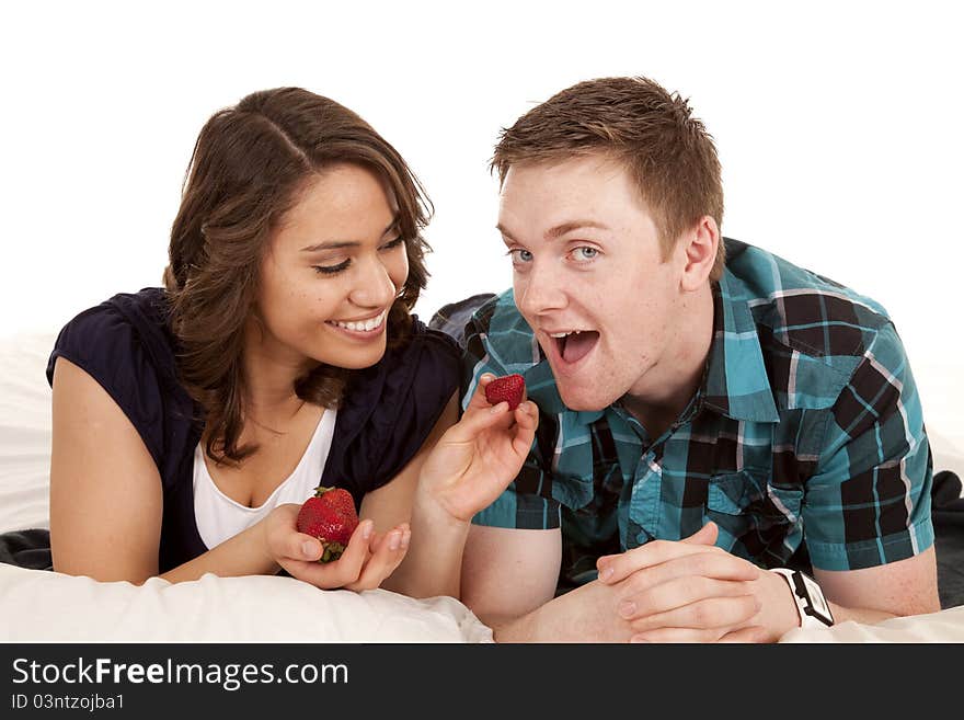 A women feeding her men a strawberry in bed. A women feeding her men a strawberry in bed.