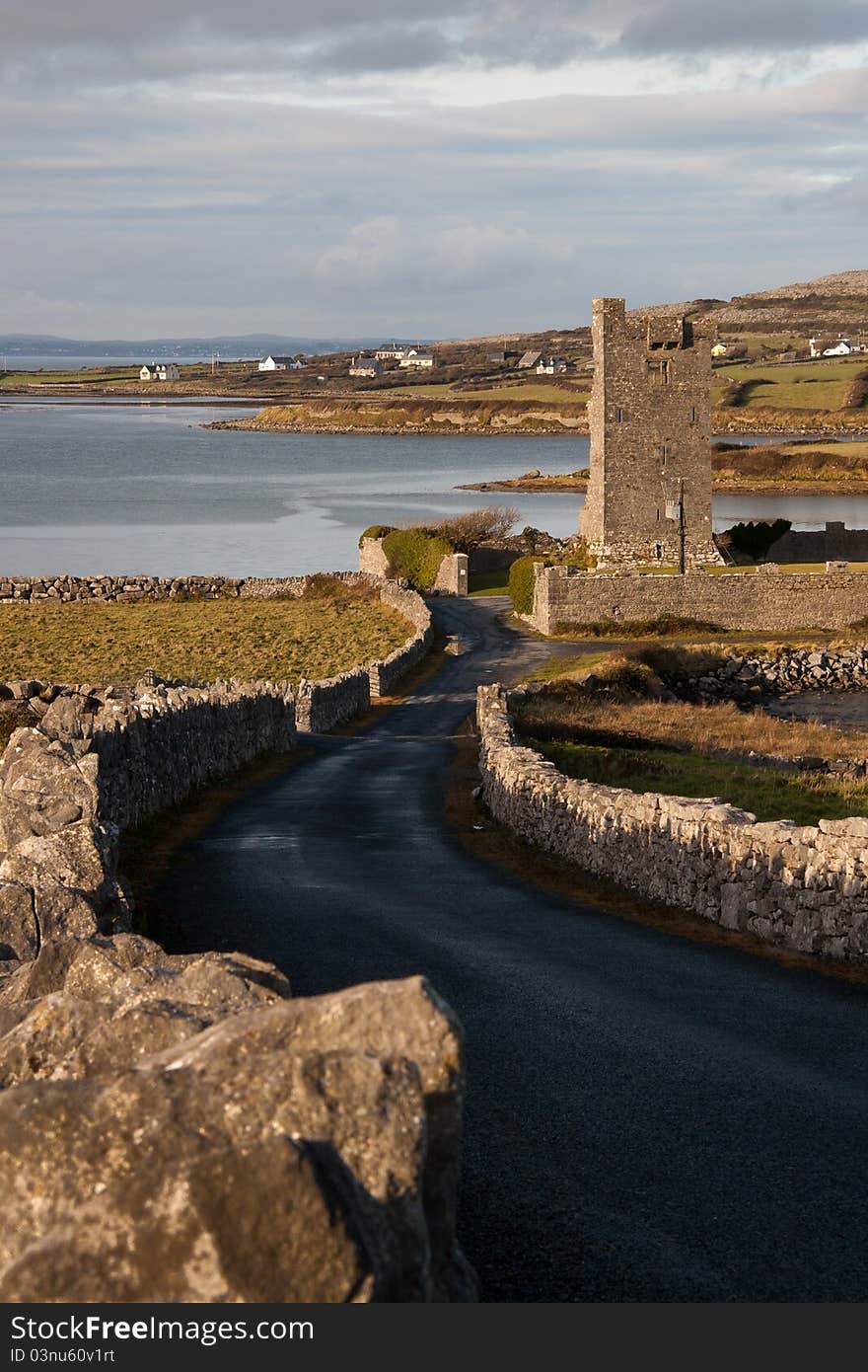 Winding road leading down to Muckinish Castle tower house on Muckinish Bay in the Irish Sea, Atlantic Ocean south of Galway in County Clare, Ireland. Winding road leading down to Muckinish Castle tower house on Muckinish Bay in the Irish Sea, Atlantic Ocean south of Galway in County Clare, Ireland