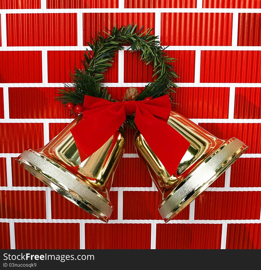 Gold Christmas Holiday Bells with Red Bow and Garland isolated on red brickwall background