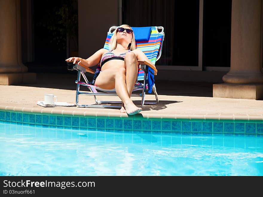 The woman is sitting near the pool. The woman is sitting near the pool