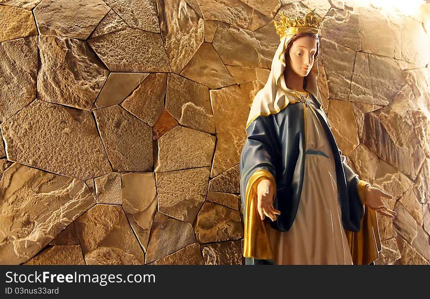 A Saint Mary statue in front of stone wall