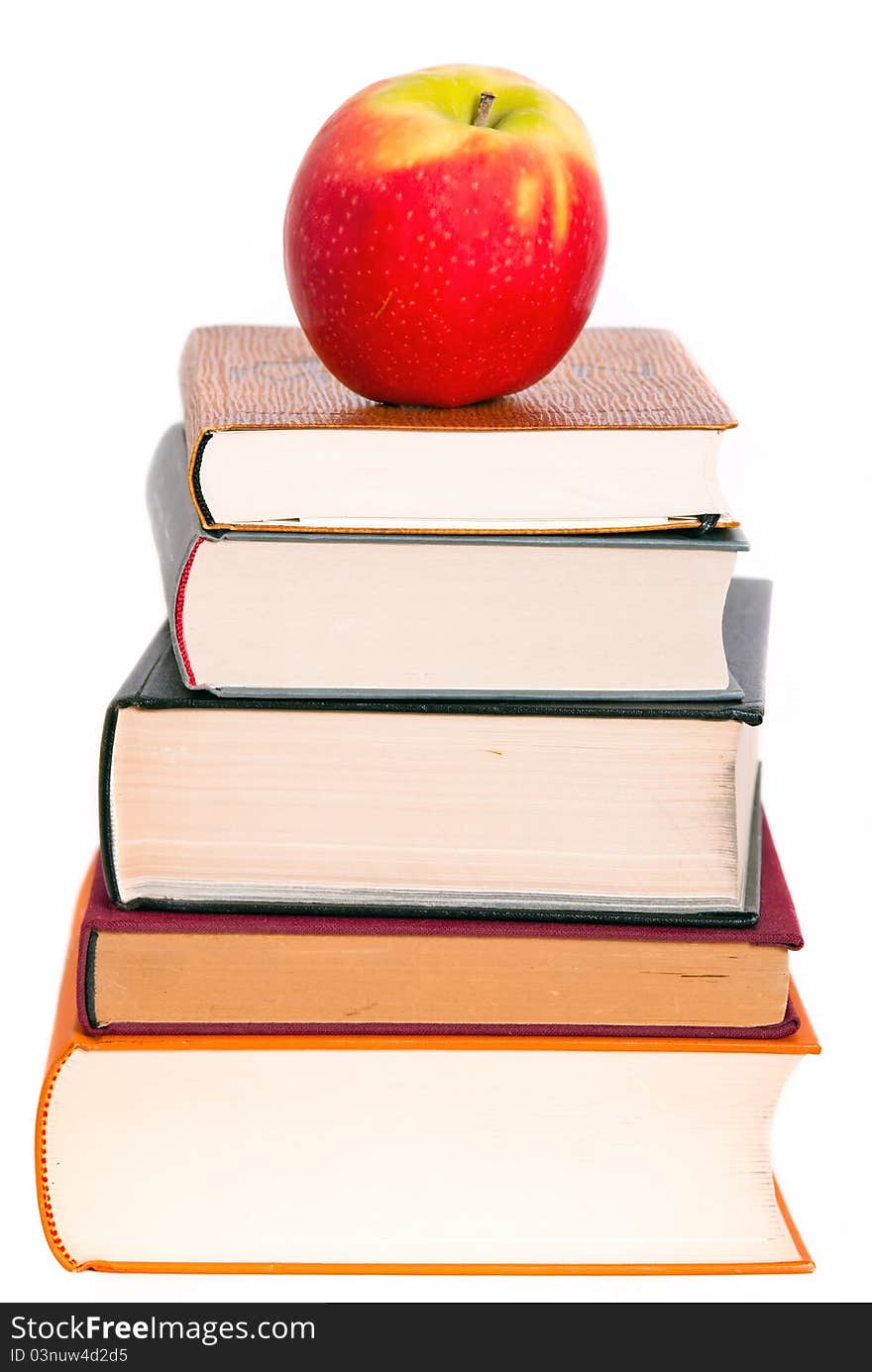 A juicy apple lies on a book pile. A juicy apple lies on a book pile