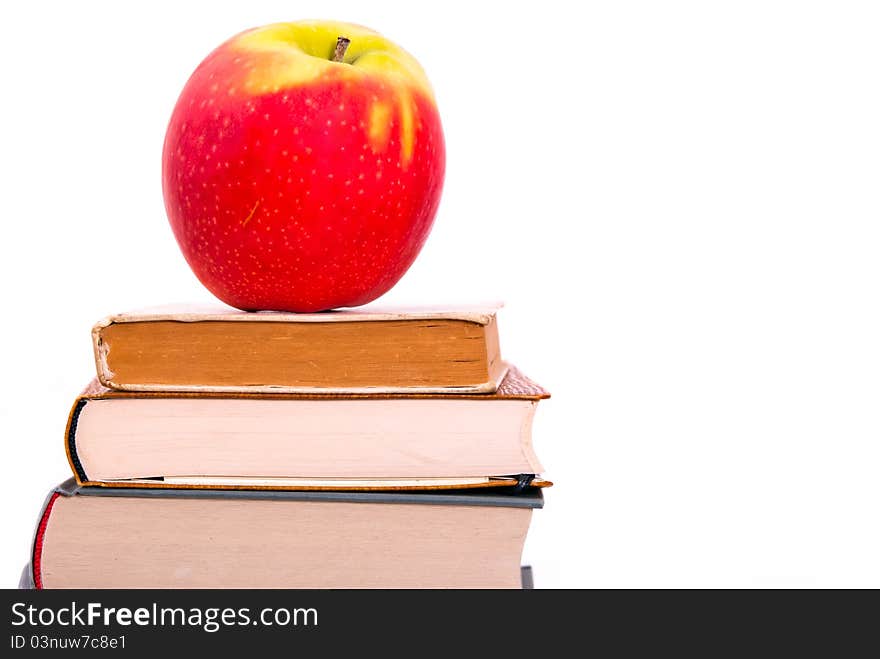 A juicy apple lies on a book pile. A juicy apple lies on a book pile