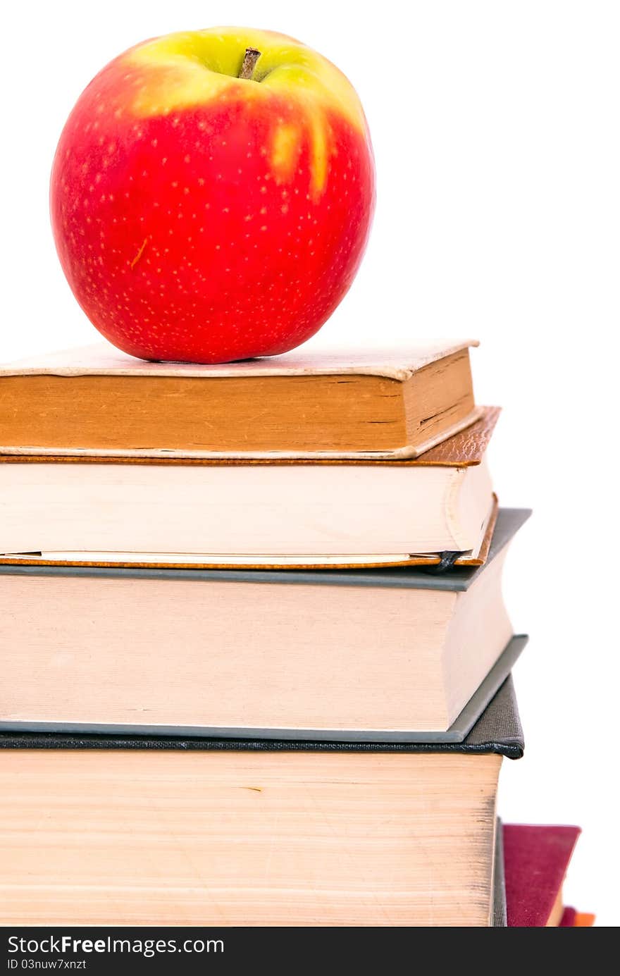 A juicy apple lies on a book pile. A juicy apple lies on a book pile