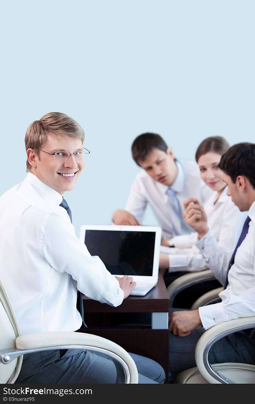 Young businessman with laptop on the background of employees in the office