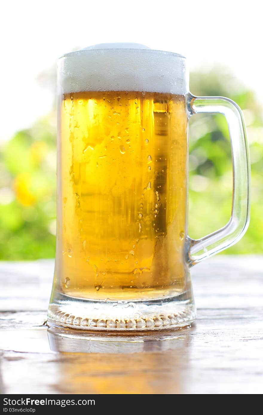 Beer mug at the table close-up, background is out of focus. Beer mug at the table close-up, background is out of focus