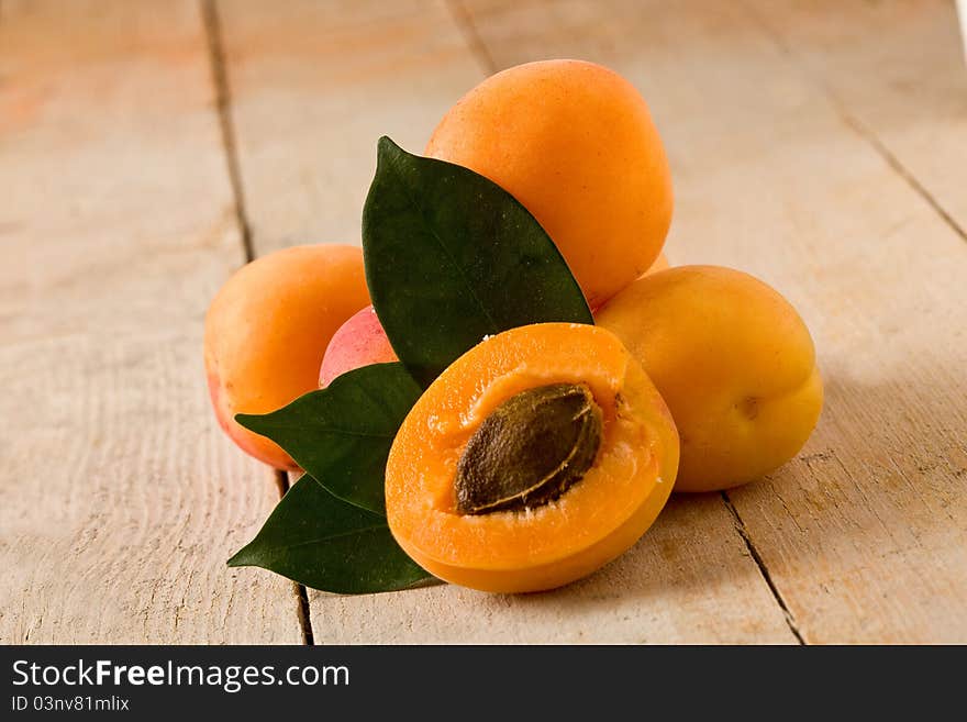 Photo of delicious tasty apricot on wooden table with leaves