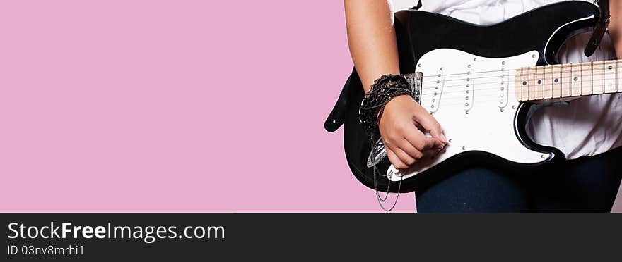 Closeup of girl playing on guitar on pink background