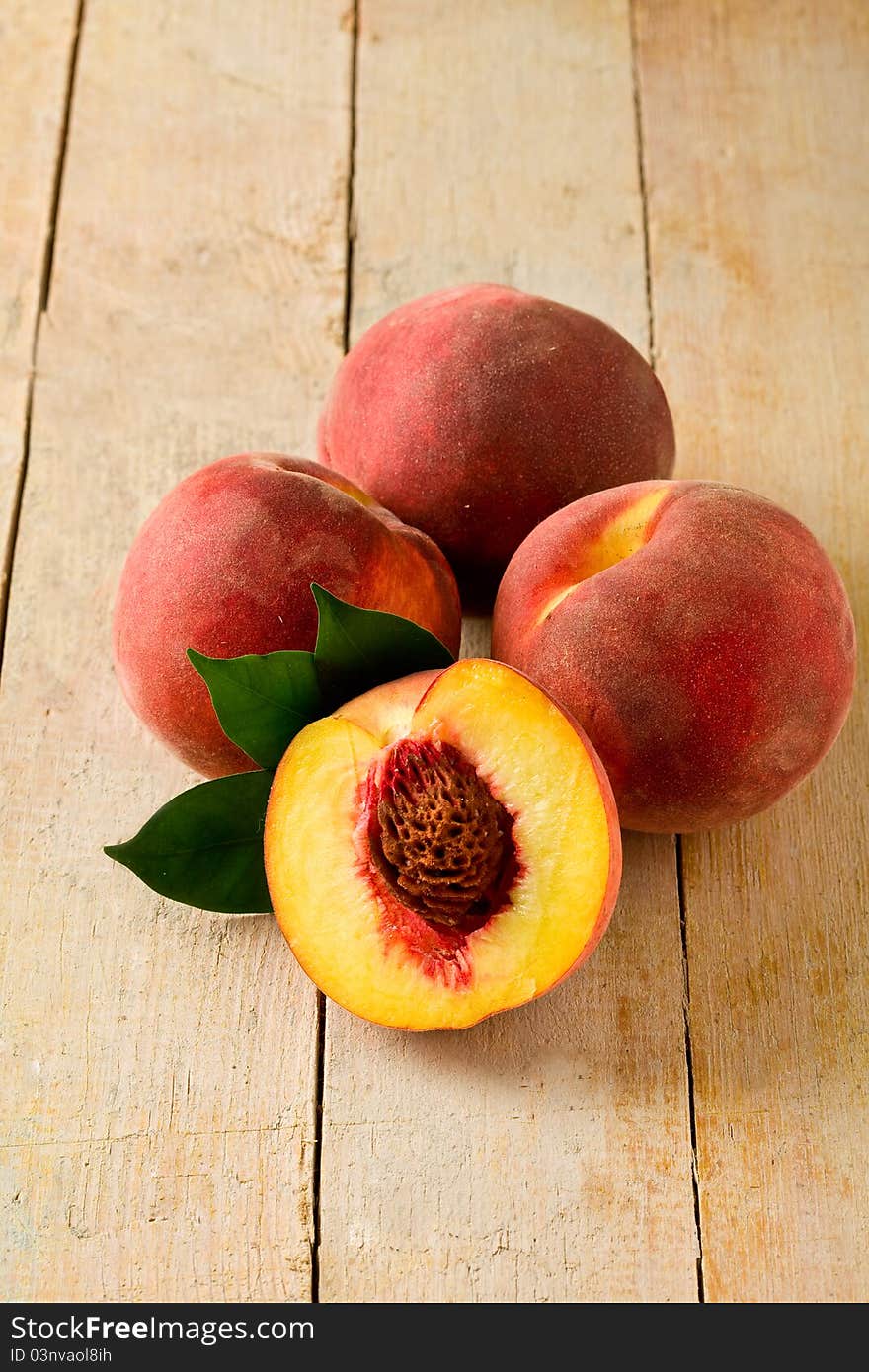 Photo of delicious peaches on wooden table with leaves. Photo of delicious peaches on wooden table with leaves