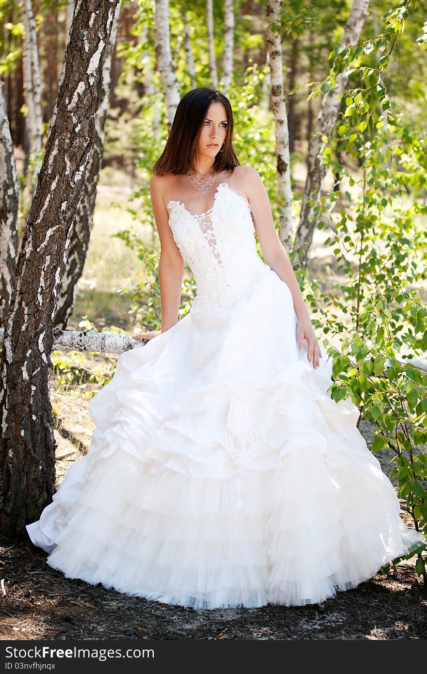 Bride with dark-brown hair posing in forest