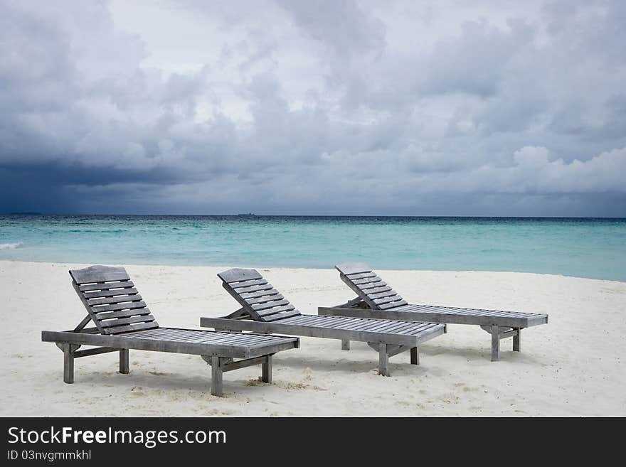 Maldives Island Monsoon. Three deckchairs on the beach