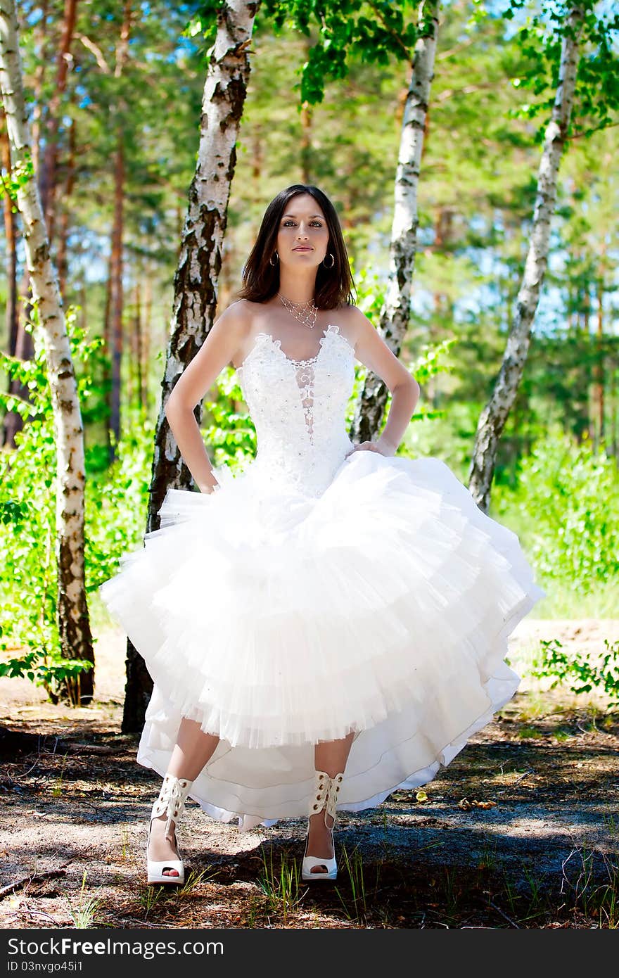 Bride with dark-brown hair posing in forest