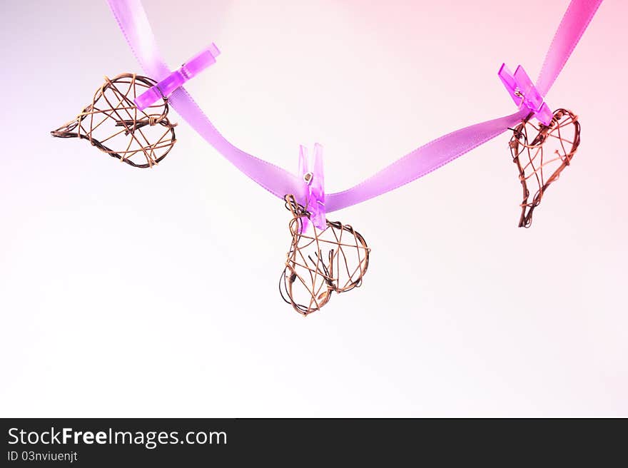 Three braided heart suspended on a purple satin ribbon with purple pegs. Three braided heart suspended on a purple satin ribbon with purple pegs