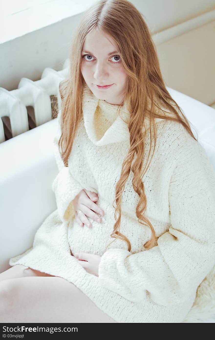 Beautiful young pregnant woman sitting on sofa