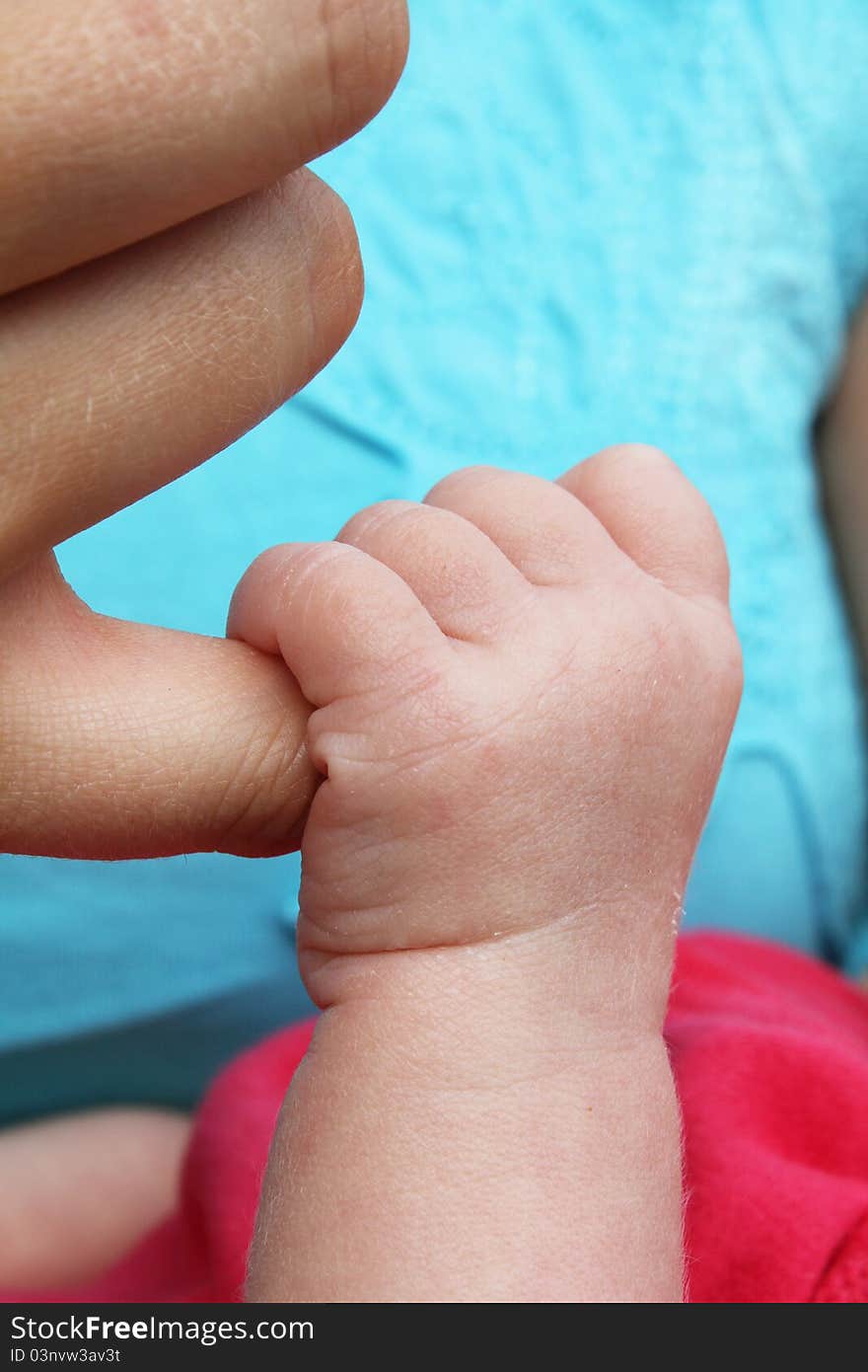 Newborn baby clutching mothers finger