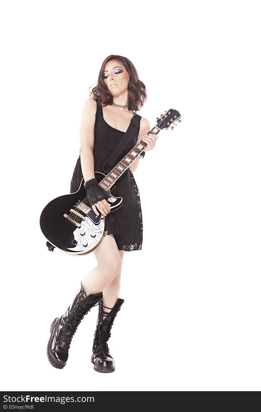 Rock star girl in a black lace dress and shiny leather boots holding a black electric guitar on a white background. Rock star girl in a black lace dress and shiny leather boots holding a black electric guitar on a white background.