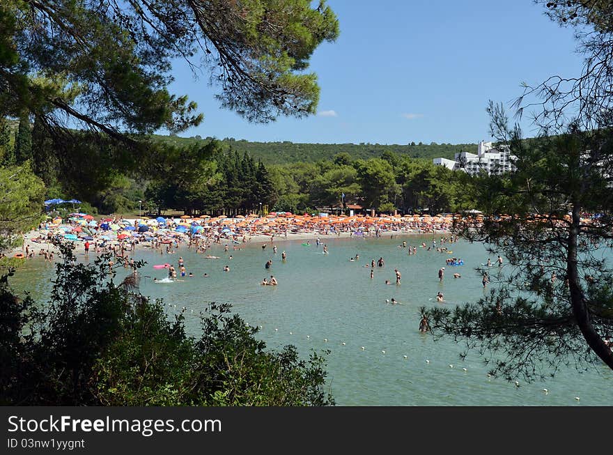 Colorful send beach crowded with people and umbrellas (Montenegro, beach Plavi horizonti)