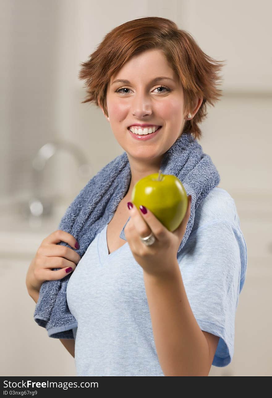 Pretty Red Haired Woman with Towel Holding Green Apple in Her Kitchen. Pretty Red Haired Woman with Towel Holding Green Apple in Her Kitchen.