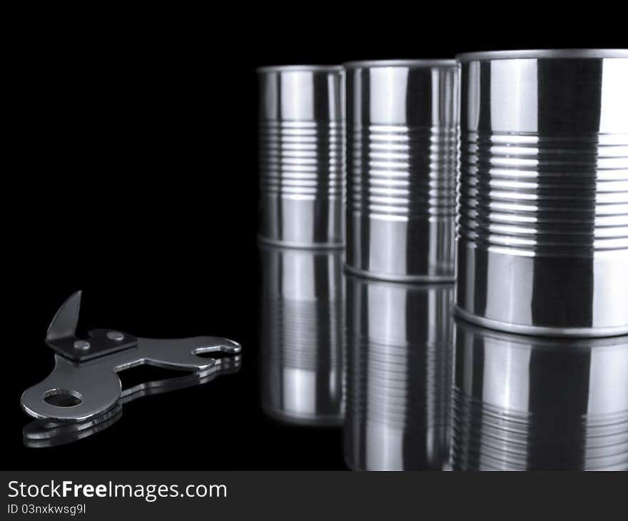 Three tin cans and an opener over a black background. Three tin cans and an opener over a black background.